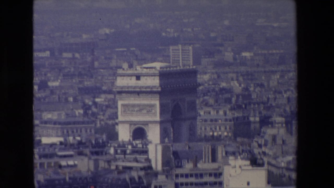 Arc de Triomphe centered low in a hazy aerial view of Paris.