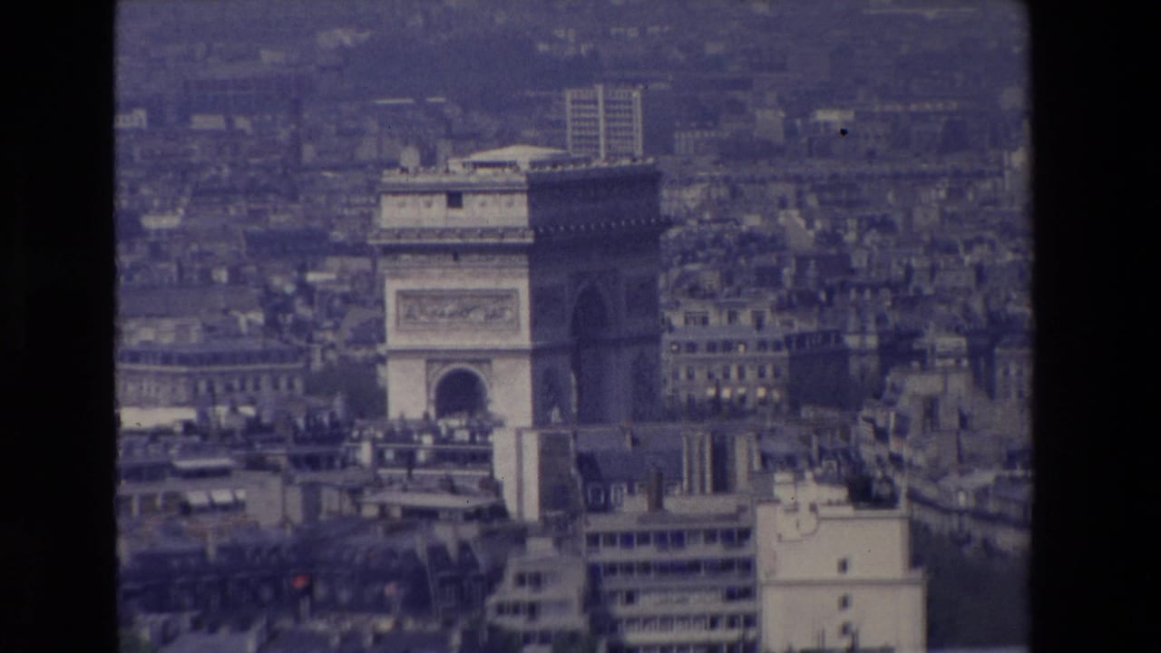 1969 Paris aerial frame with the Arc de Triomphe centered among dense buildings under a blue, hazy exposure.