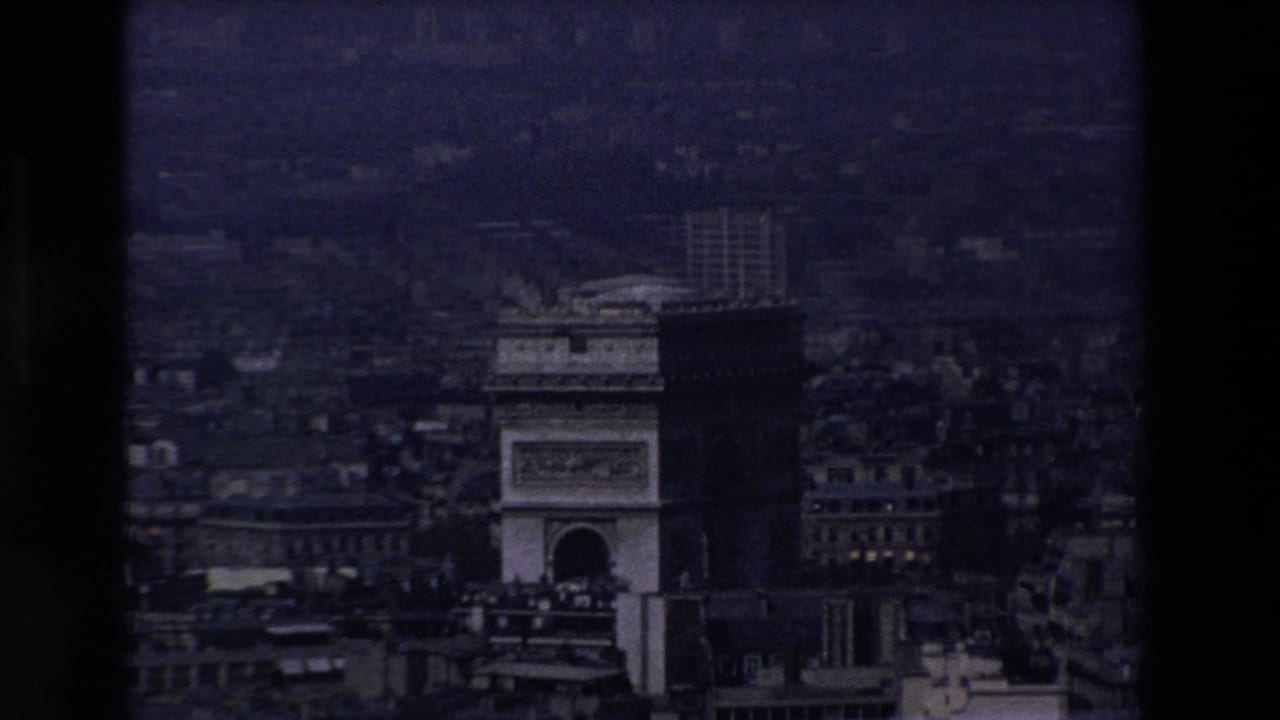 Darker aerial view of the Arc de Triomphe and surrounding Paris buildings.