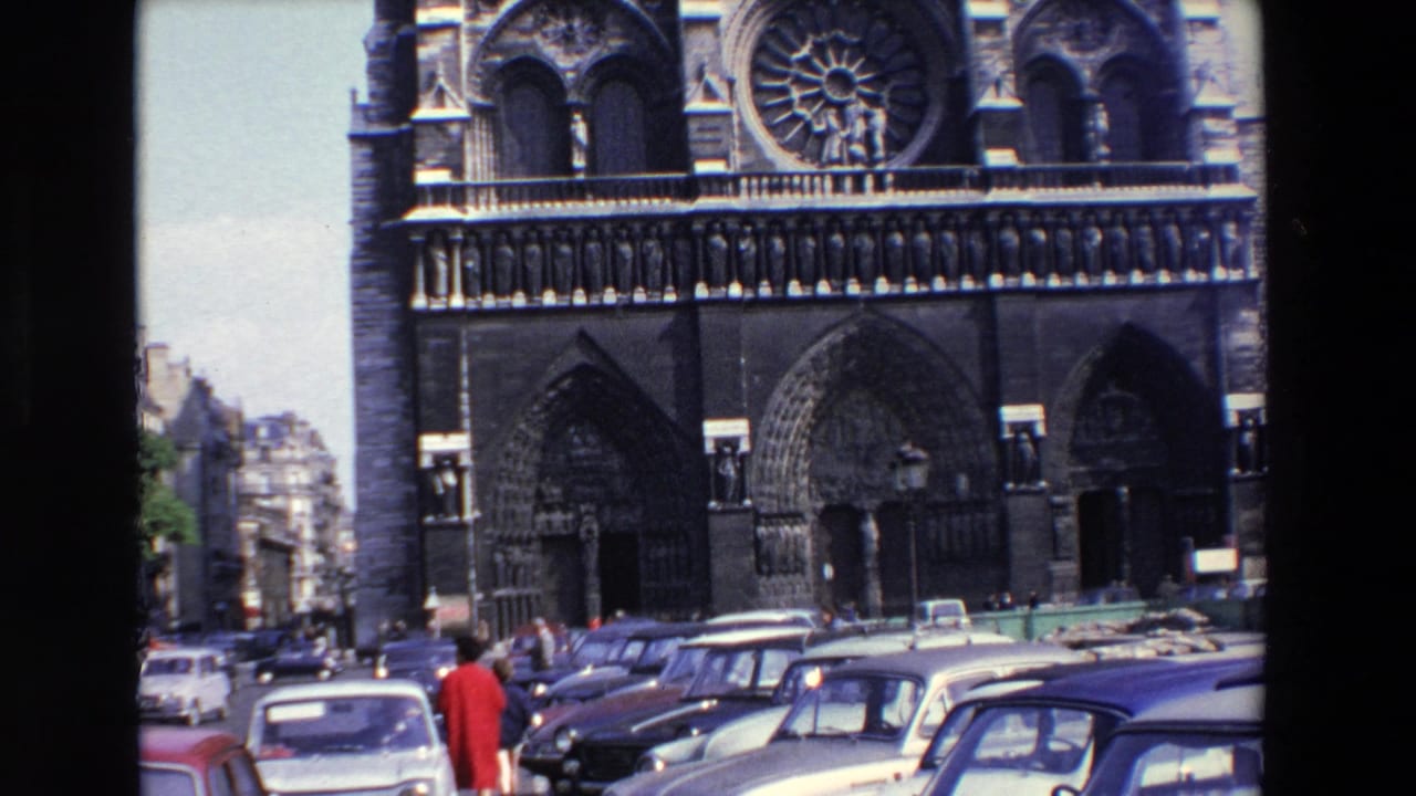 1969 Paris 8mm frame showing Notre-Dame Cathedral's rose window and arched entrances above parked 1960s cars, with pedestrians crossing the foreground street area.