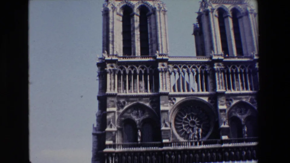 1969 Paris travel frame showing Notre Dame's western facade from a low angle, including tower openings, the rose window, rows of Gothic arches, and pale sky.