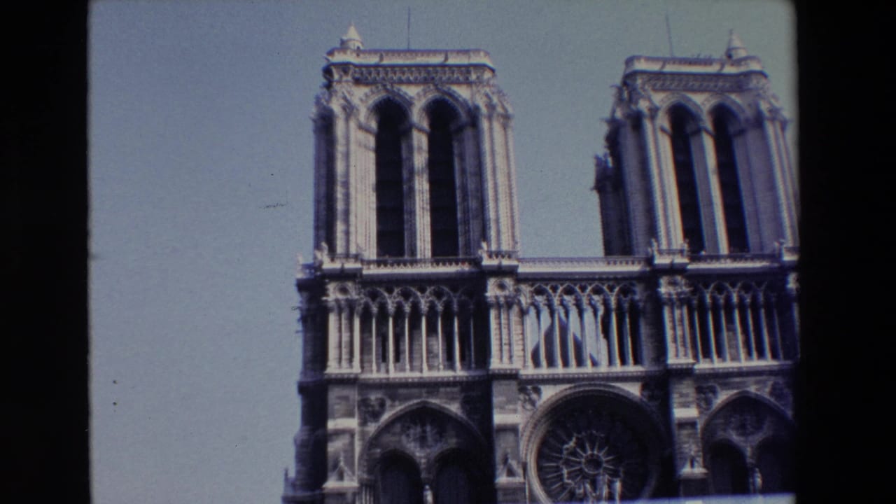 Paris home-movie frame of Notre Dame's front facade, with the towers, upper arcade, and rose window partly cropped by the film frame.