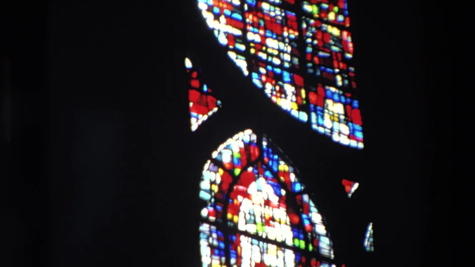 Supported 1969 Paris 8mm frame showing several luminous stained glass sections, including a lower arched panel, inside a dark church space.