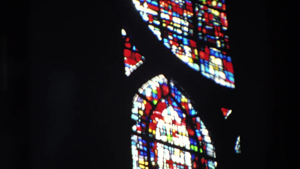 Supported Paris 1969 frame with bright red, blue, yellow, and white stained glass windows framed by deep interior shadow.