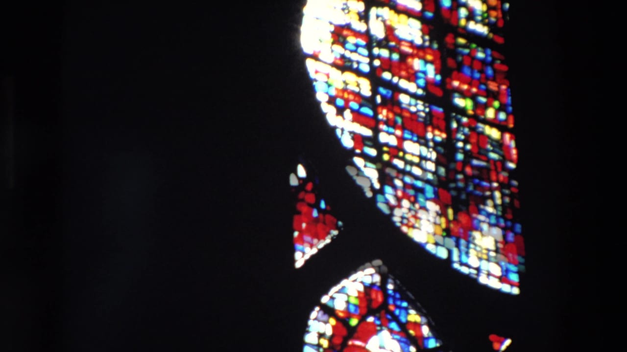 Bright stained glass fragments and dark interior space.