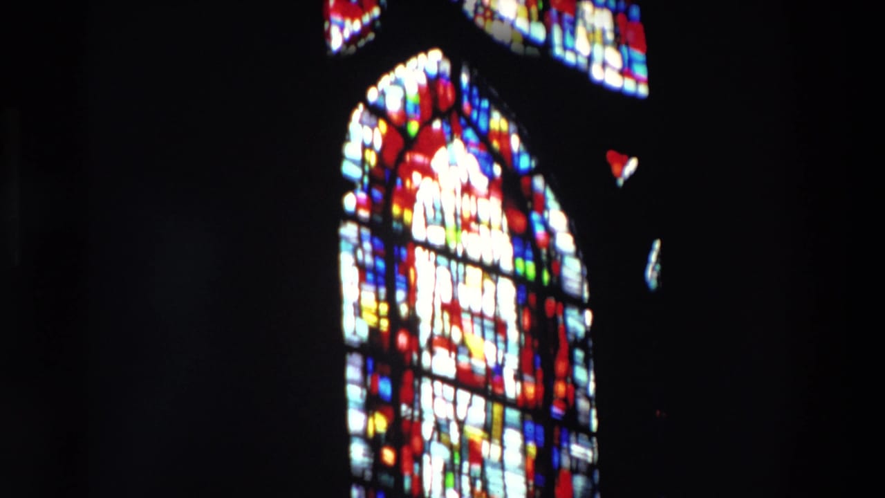 Bright arched stained-glass window framed by darkness.