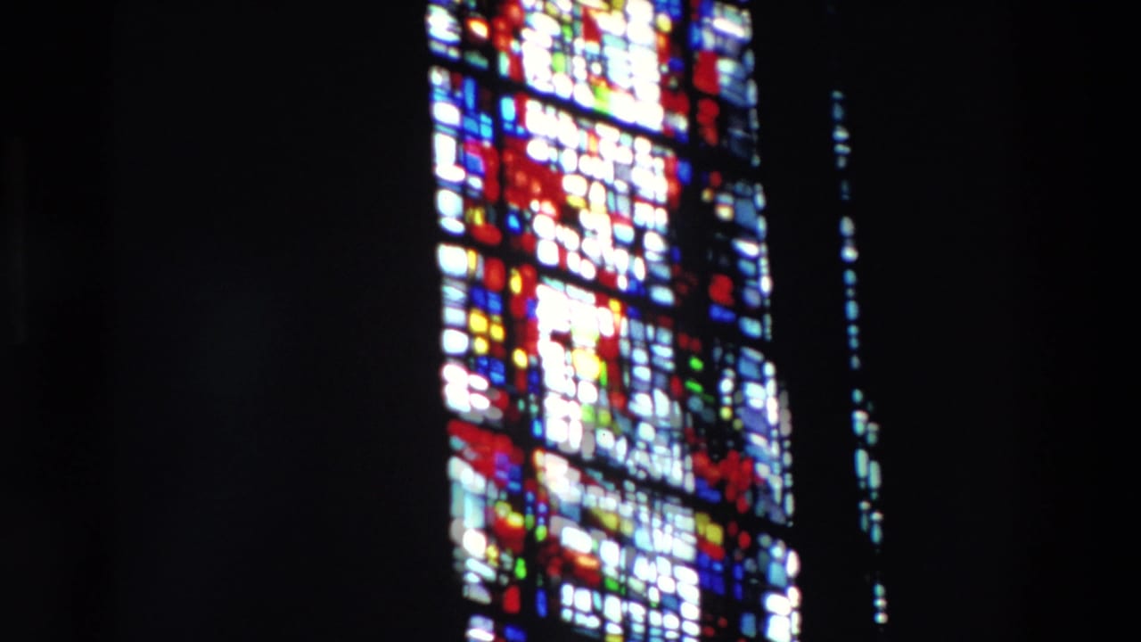 Soft-focus stained glass window glowing in a dark Paris church interior, supported by 1969 clip metadata.