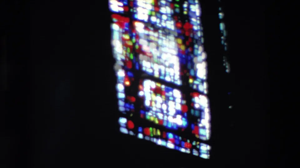 Lower stained glass sections glow with red, blue, yellow, and green panes in soft 8mm focus.