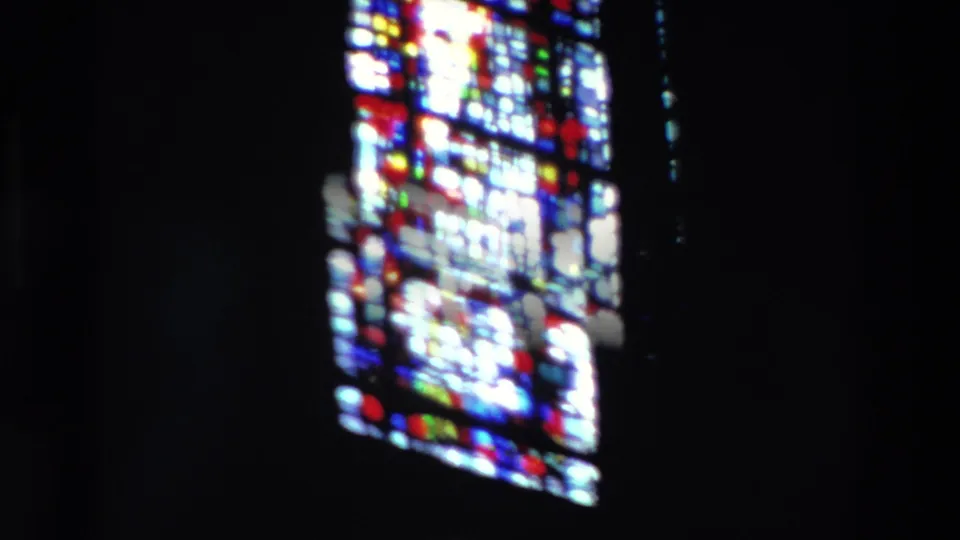 1969 Paris 8mm frame showing bright stained glass panes against a nearly black church interior, with one larger window on the left and another on the right.