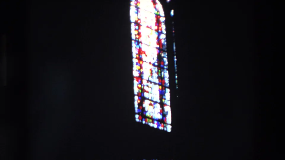 1969 Paris 8mm frame centered on a tall stained glass church window, with colored panes standing out from the dark interior wall.