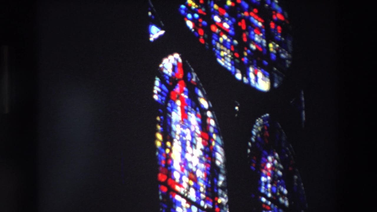 Colorful stained glass forms glowing against deep shadows.