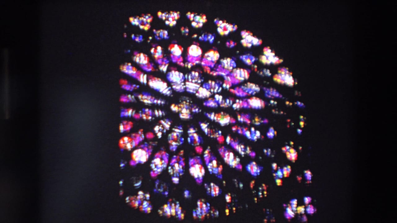 Circular rose window glowing with purple, red, and white stained glass.