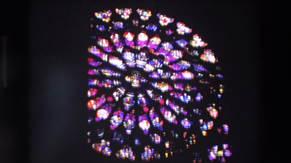 A circular rose window in a Paris church glows in purple, red, blue, and white tones within a dark 1969 8mm frame.