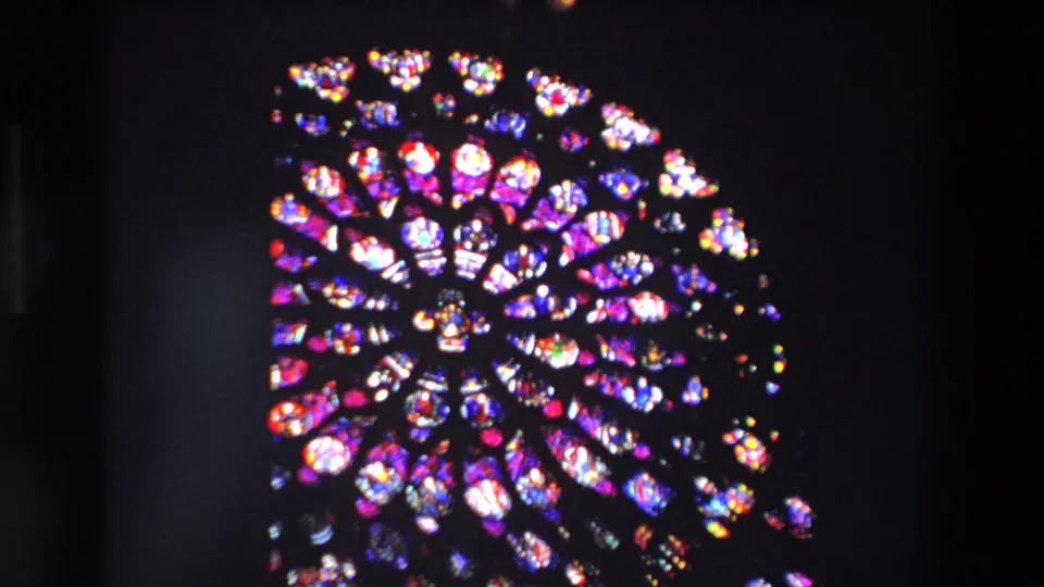 A rose window remains framed in a dark Paris church interior, with smaller stained glass sections visible near the lower edge of the 1969 footage.