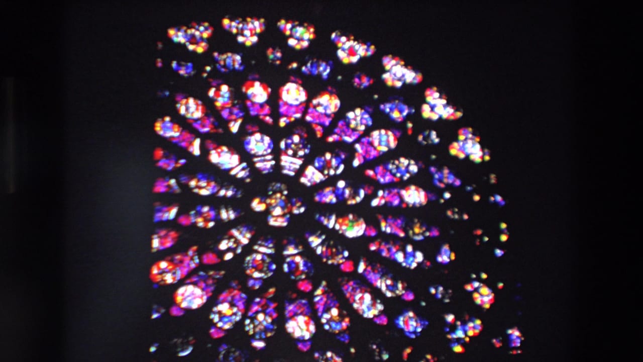1969 Paris 8mm frame showing a wide rose-window view with vivid red, blue, purple, and white stained glass set in a dark cathedral interior.