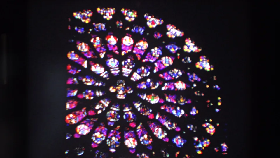 1969 Paris 8mm frame showing a wide rose-window view with vivid red, blue, purple, and white stained glass set in a dark cathedral interior.