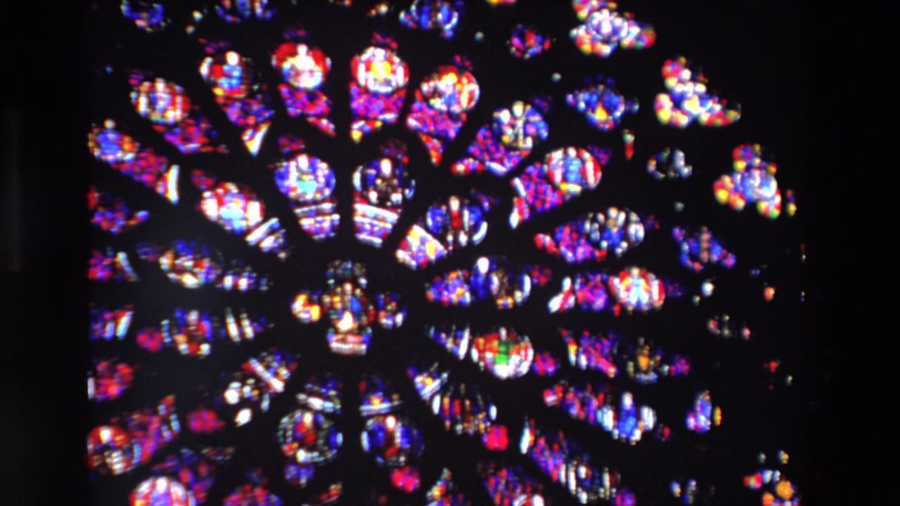 Closer view of the upper stained glass rose window with bright colored panes.