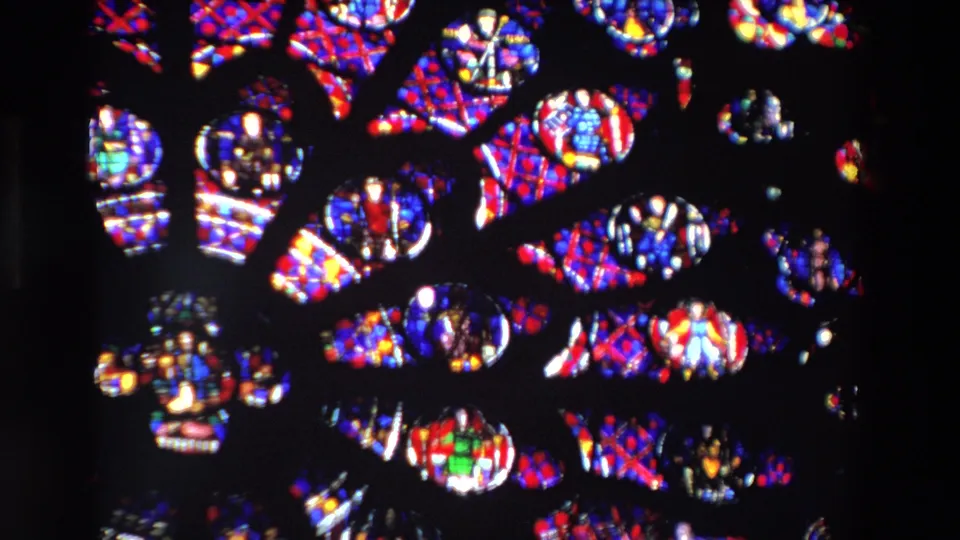 Close 1969 Paris 8mm frame of stained glass details, showing patterned panes, small religious figures, and bright color against black leading.