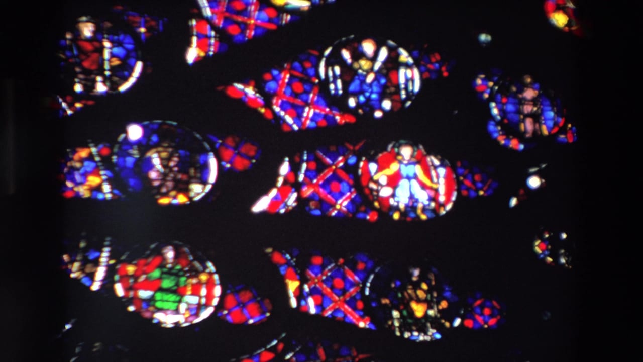 Close view of colorful stained glass sections separated by dark window framing.