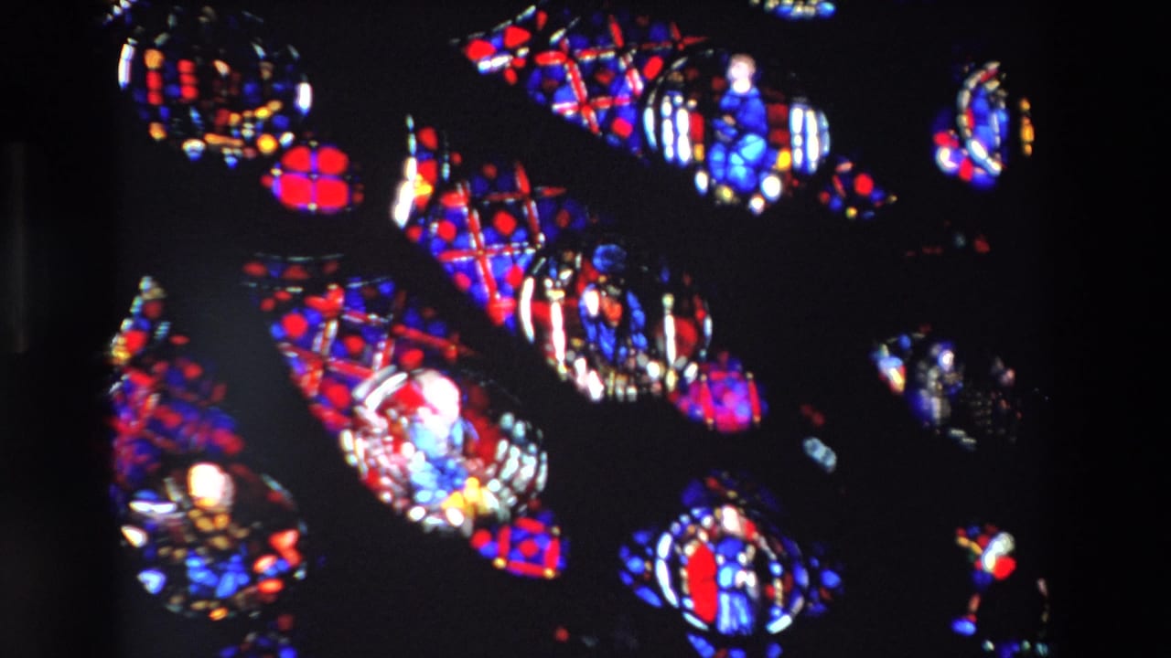 Bright stained glass figures and patterns fill most of the frame.