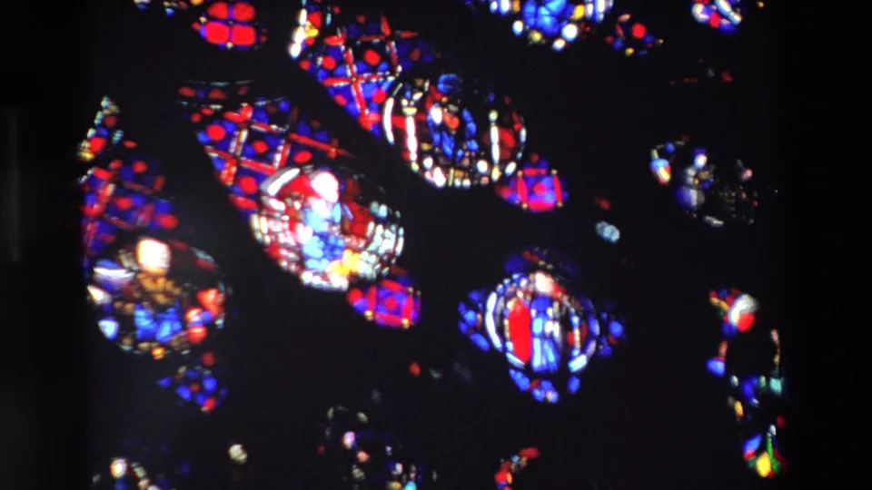 Close 1969 Paris frame showing overlapping stained glass forms, small religious figures, dark negative space, and soft 8mm grain.