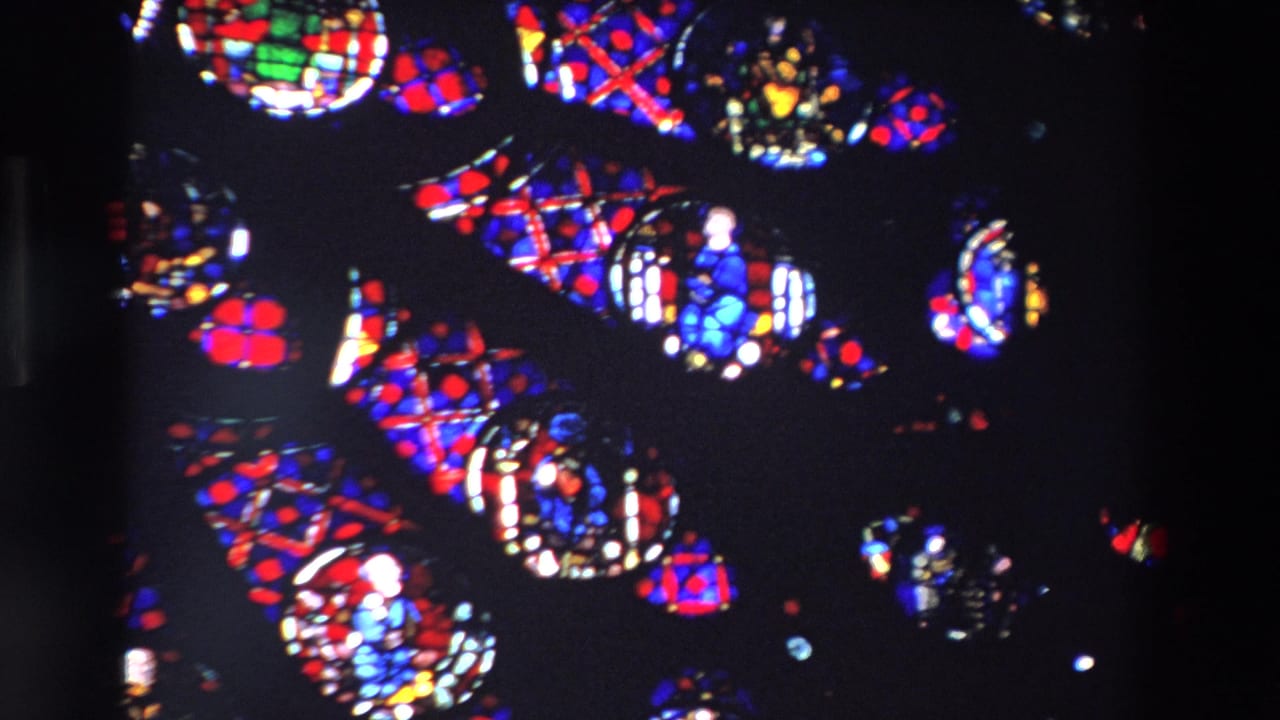 Stained glass panels with religious figures and patterned red and blue sections.