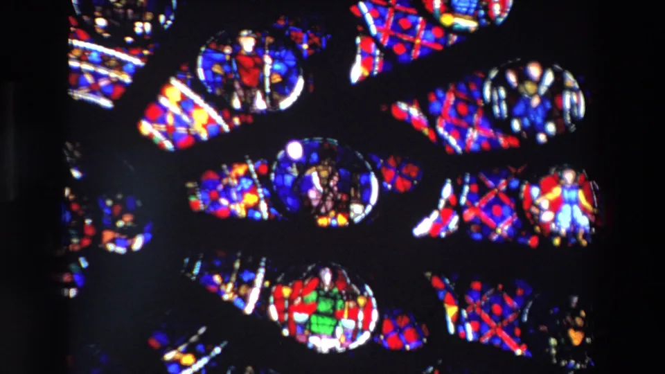 1969 Paris frame with multiple stained glass scenes, including small human figures in the glass, divided by dark cathedral window structure.