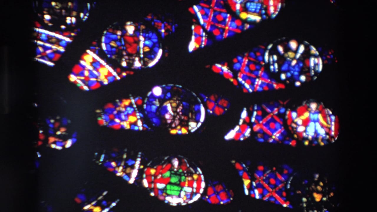 1969 Paris 8mm frame showing kaleidoscopic stained-glass fragments in red, blue, yellow, green, and white against deep black space.