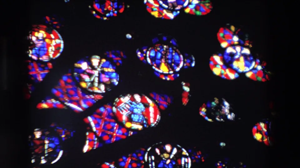 1969 Paris 8mm frame showing bright stained-glass pieces clustered in a rotating abstract arrangement, with circular fragments and colored geometric panes.