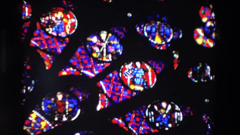 1969 Paris 8mm frame with repeated red and blue stained-glass patterns, small circular glass details, and dark space emphasizing the rotating abstract effect.