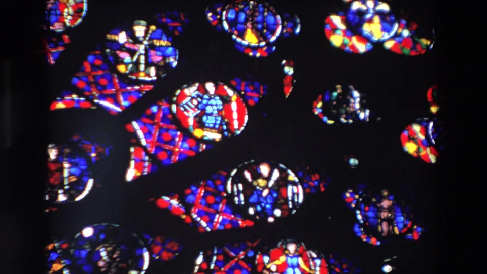 1969 Paris 8mm frame showing bright stained-glass motifs and small religious figure details surrounded by dark church interior shadows.