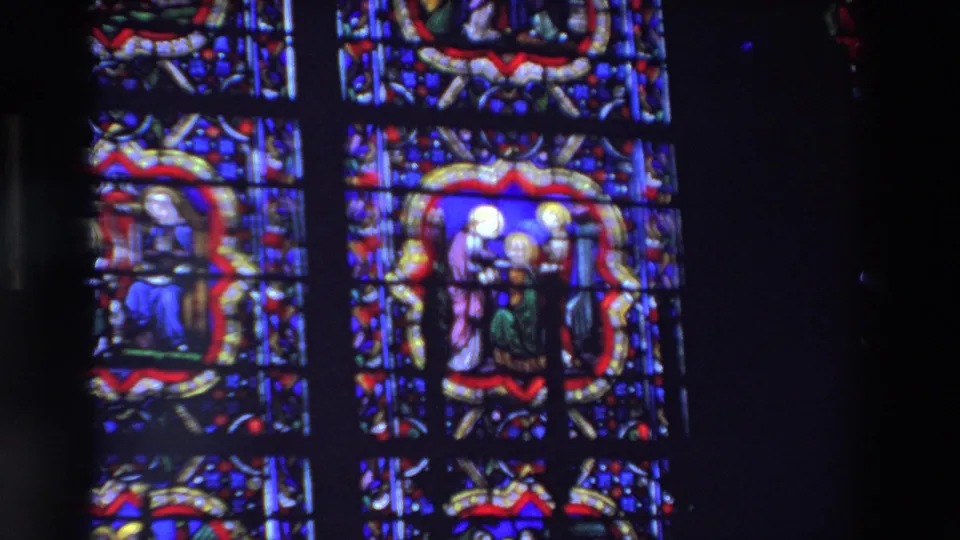 1969 Paris 8mm frame showing a larger stained-glass window section with robed religious figures, blue panels, red borders, and heavy lead divisions.