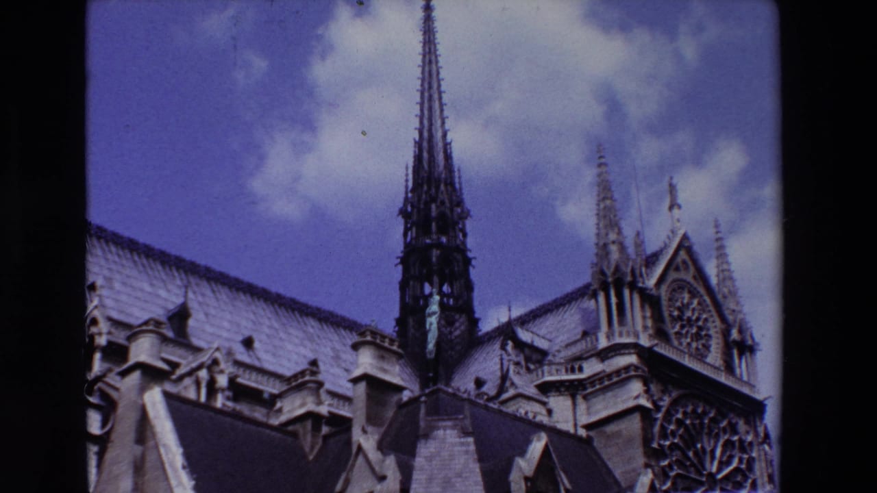 Notre Dame upper facade with spire, roof, and rose window against clouds.