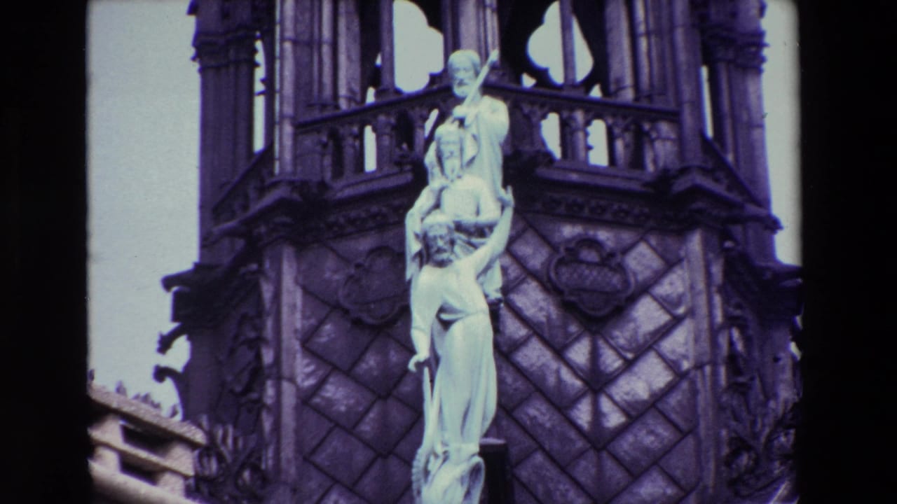 Closer view of a pale sculptural group on a dark Gothic spire.