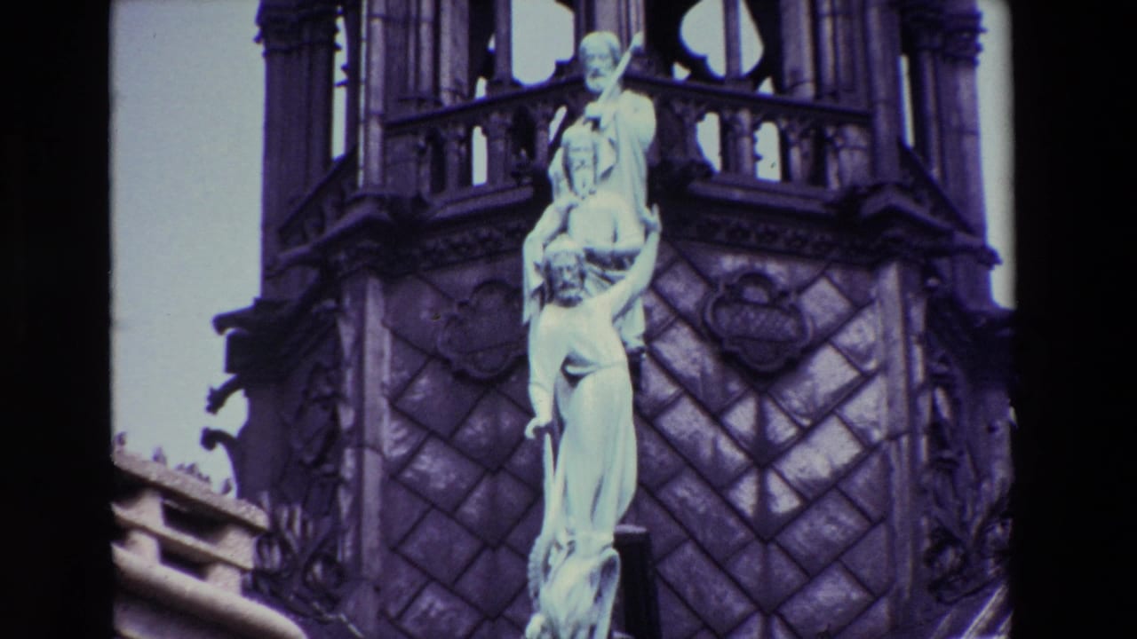 1969 Paris 8mm frame showing a pale stone statue set against carved Gothic cathedral architecture with dark scan edges and cool color shift.