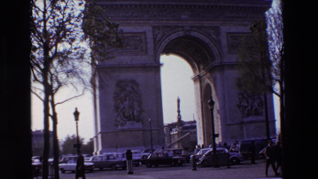 Paris, France in 1969, with the Arc de Triomphe framed by trees and street lamps as pedestrians and cars move through the foreground.
