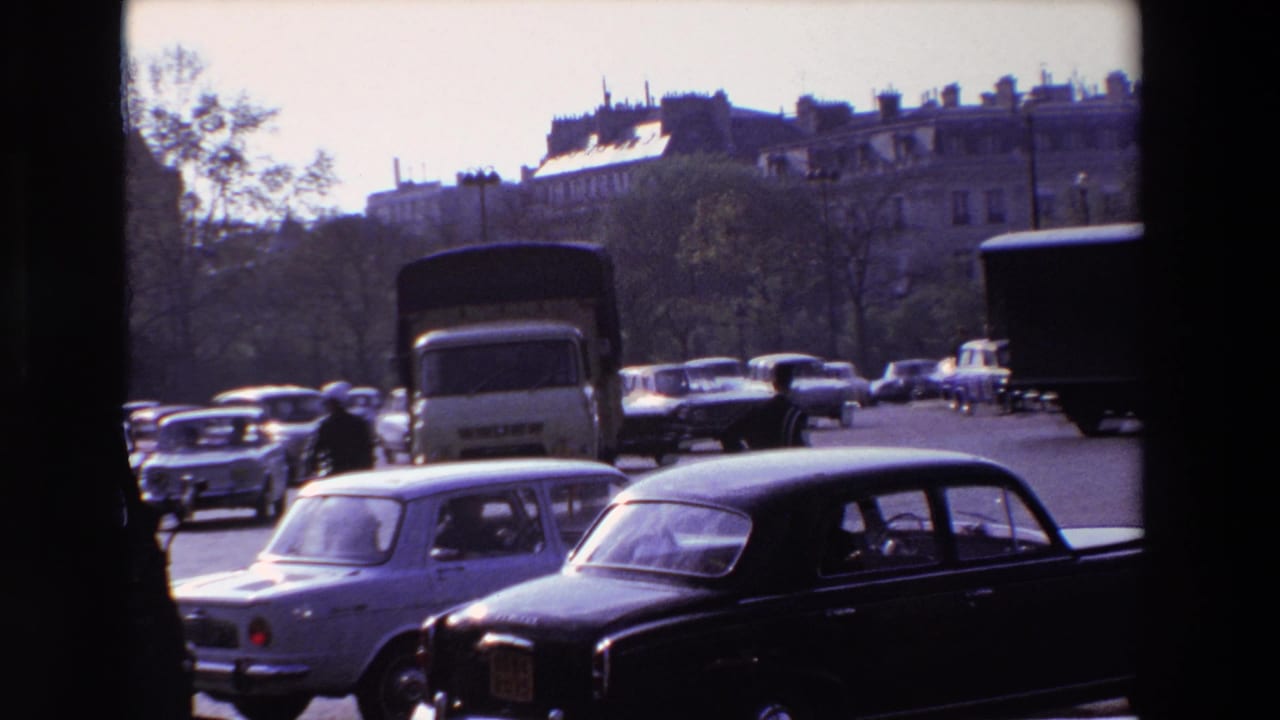 Cars and trucks move past a uniformed traffic policeman near apartment buildings.