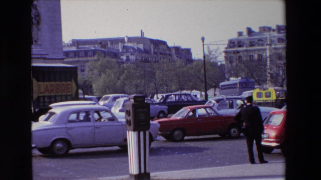 Cars, taxis, and a pedestrian crossing a broad city intersection.