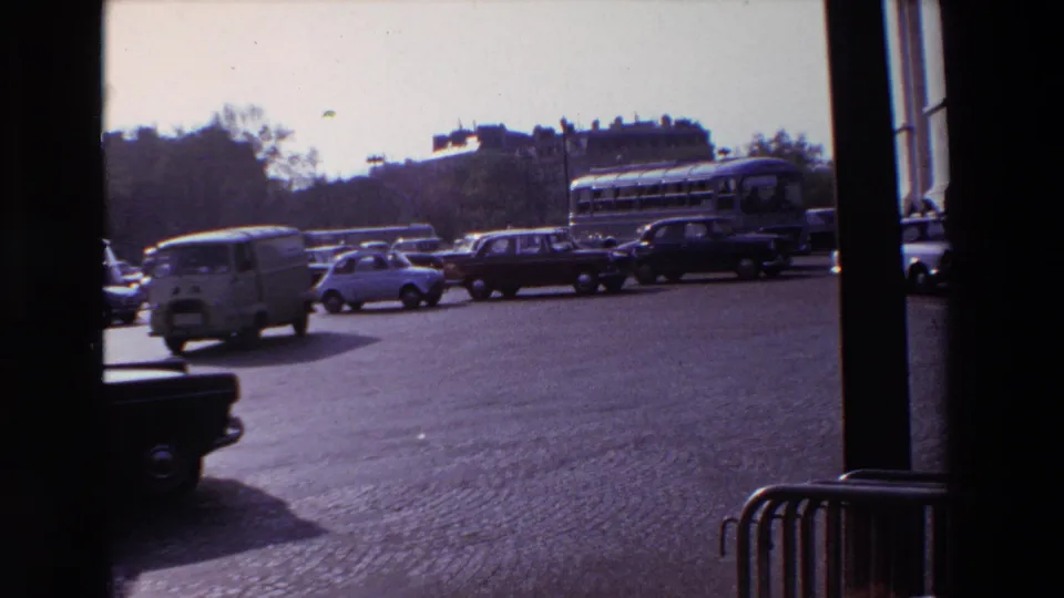 The final frame shows 1969 Paris traffic with a small van, compact cars, a bus, cobblestones, and foreground architectural framing from the filming position.