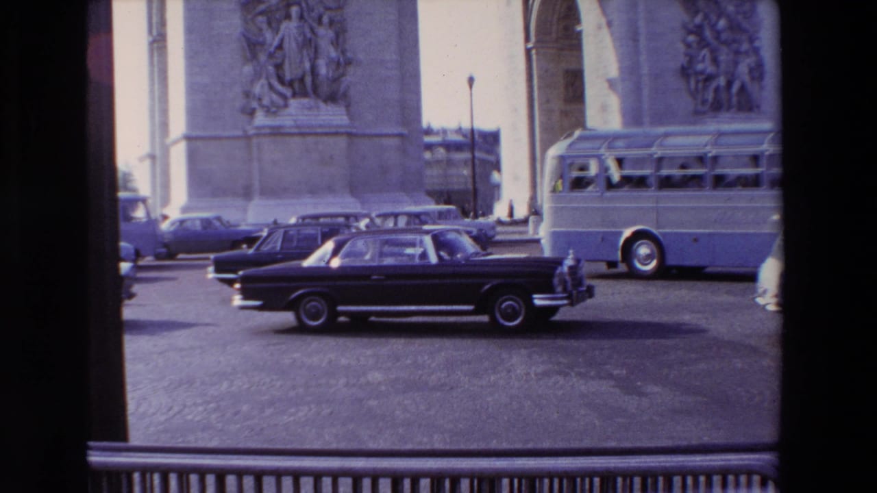 Cars and a tour bus move through traffic below the Arc de Triomphe.