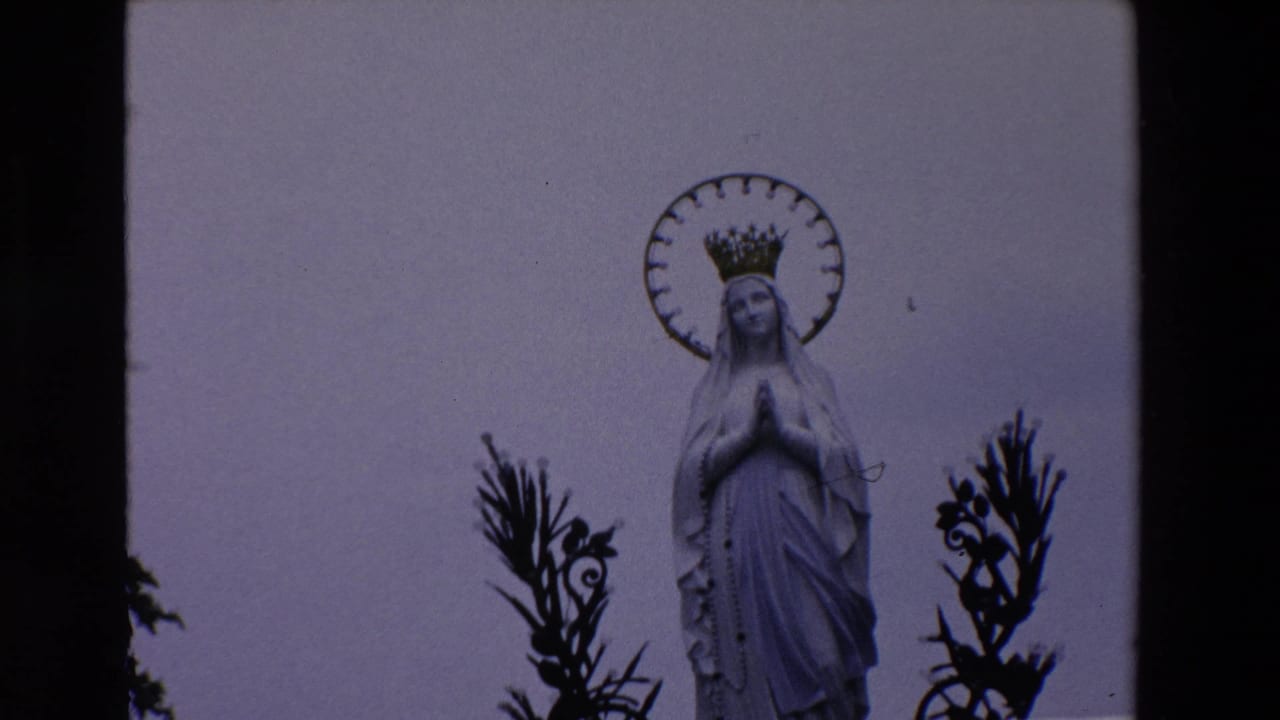 White Virgin Mary statue with halo and crown centered against a pale sky.
