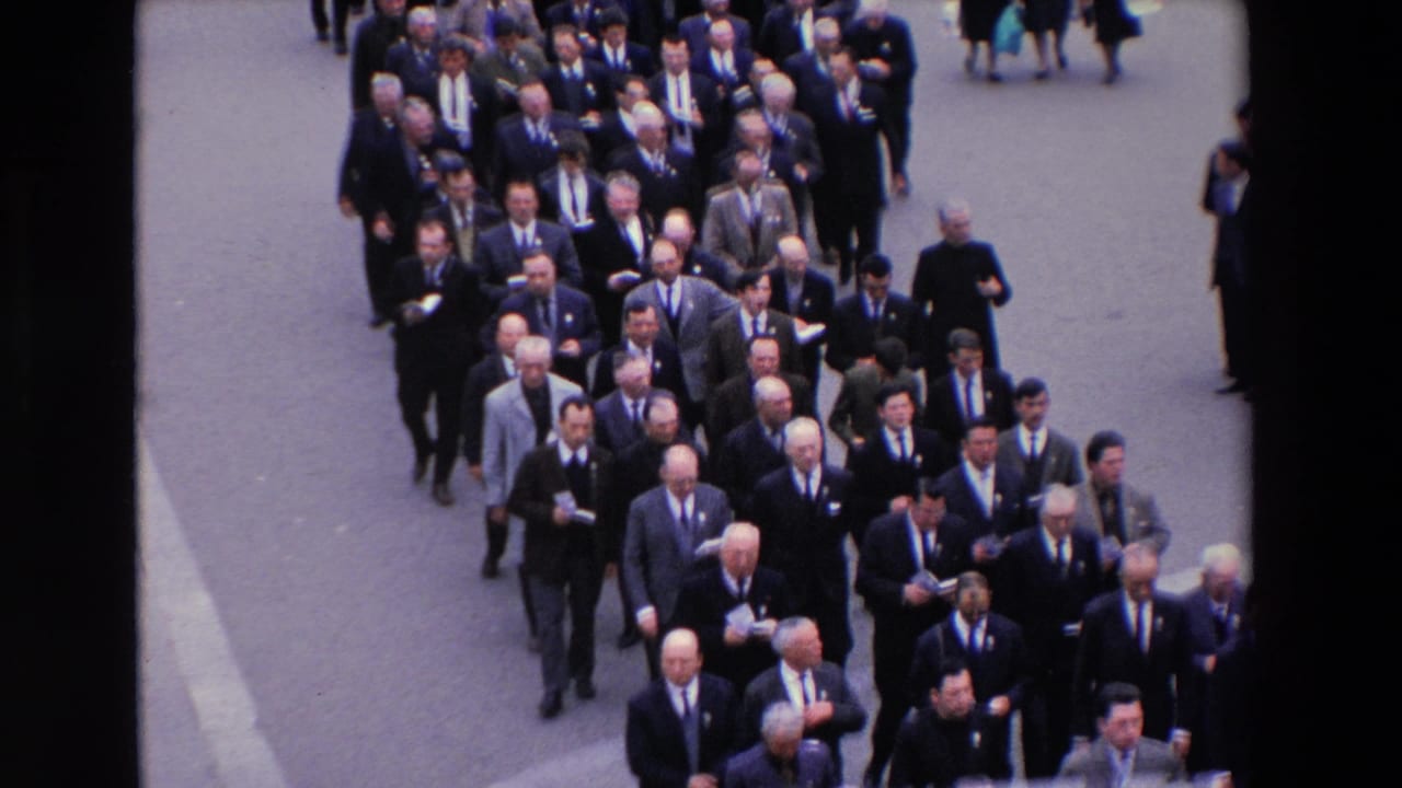 High-angle Paris street frame from 1969 showing a dense procession of suited men moving forward, with a few pedestrians visible around the edges.