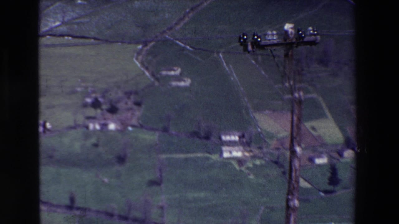 Rural fields and houses with a utility pole near the right edge.