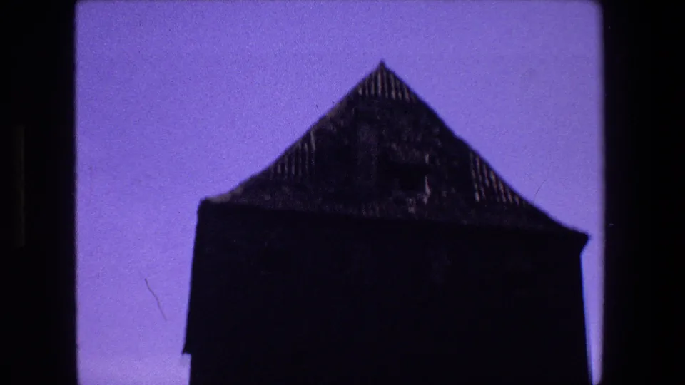 Strasbourg 8mm frame showing a dark silhouetted structure with a steep pointed roof against a purple-blue sky.