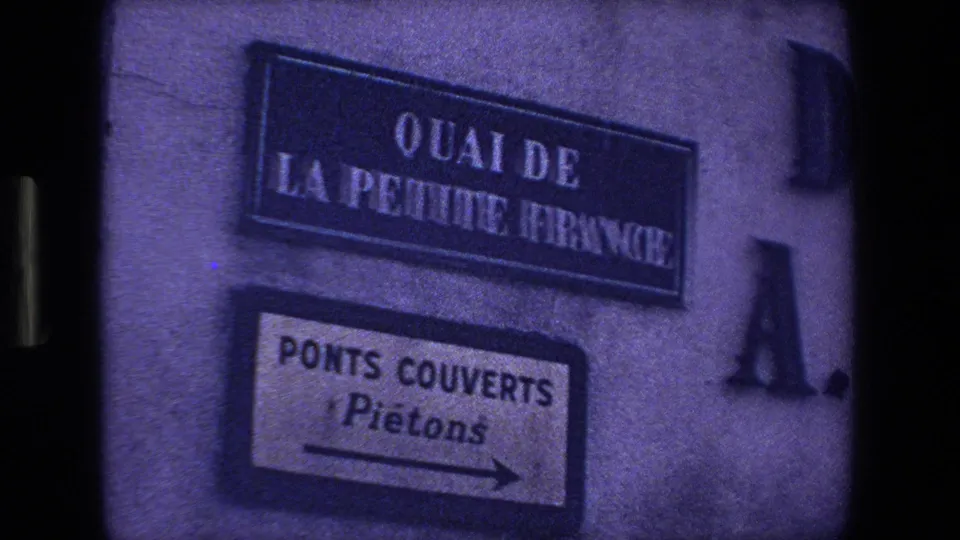 1970 Strasbourg frame showing a wall-mounted Quai de la Petite France sign above a pedestrian direction sign for Ponts Couverts.
