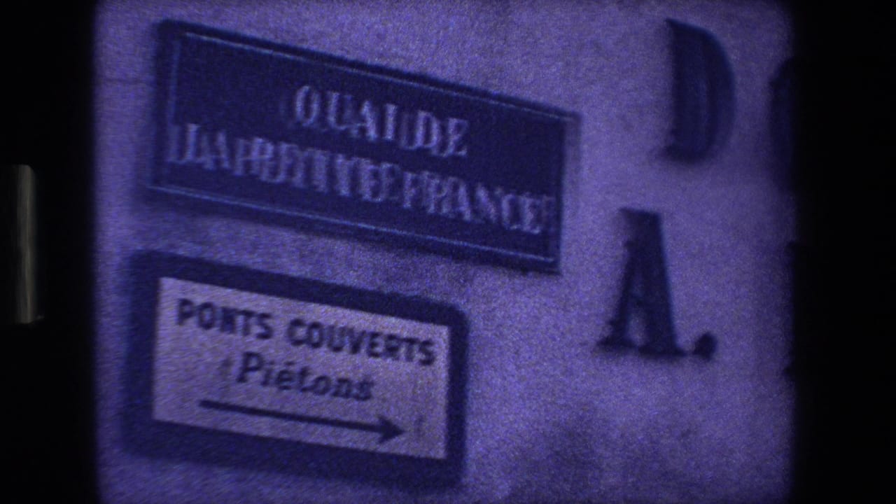 Blurred street and pedestrian signs on a wall with large mounted letters nearby.