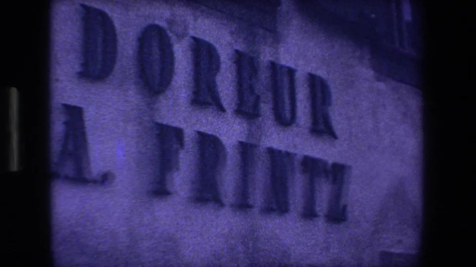 1970 8mm Strasbourg frame showing raised facade lettering reading DORLEUR A. PRINTZ on a textured wall.
