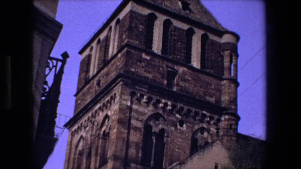 The final frame shows the upper section of a historic stone tower in Strasbourg, including arched windows, a steep roofline, and handheld film framing.