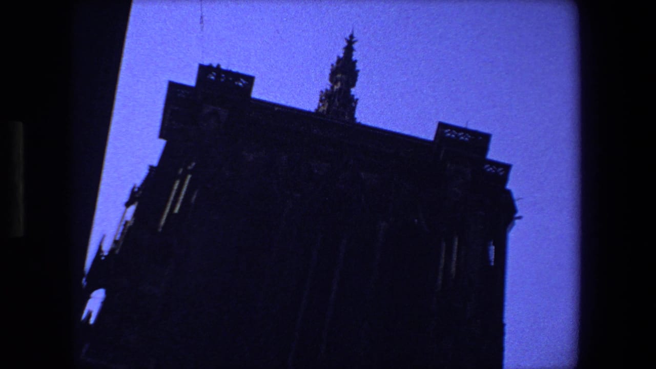 Silhouetted Gothic building with a pointed spire against blue sky.