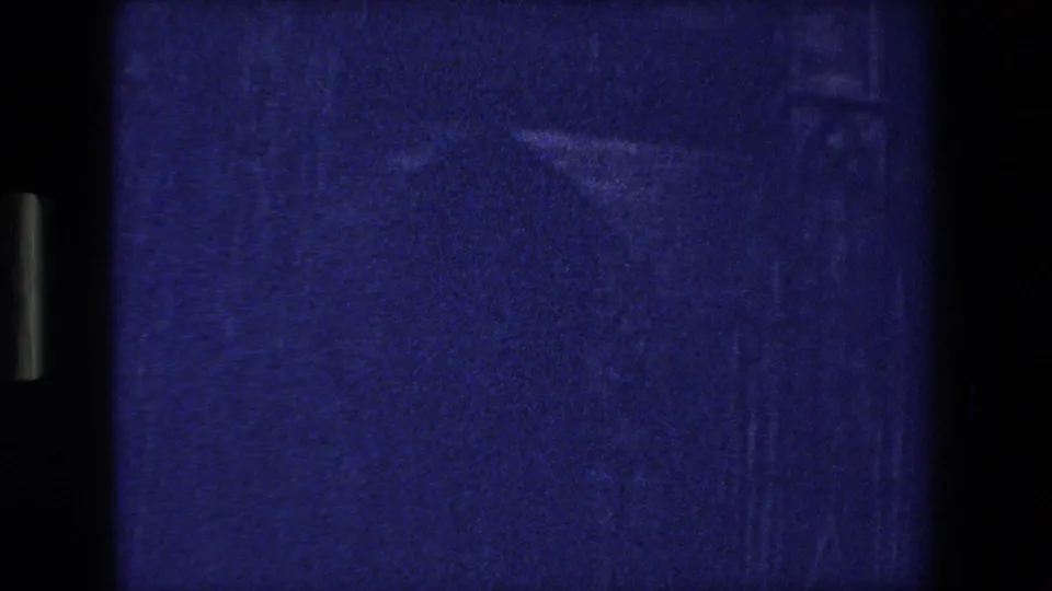 Underexposed 8mm frame from the 1970 Strasbourg footage, dominated by blue-purple grain, vertical gate shadows, and faint marks from the film scan or projection.